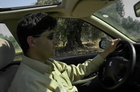 Fareed driving me to a site to photograph, ancient olive tree in the background, 2007 c.